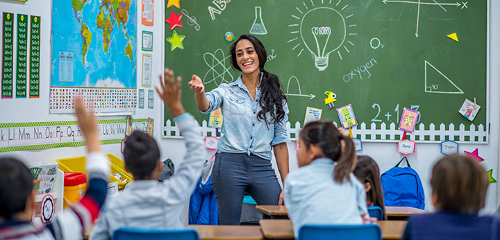 Children raising their hand in a classroom.